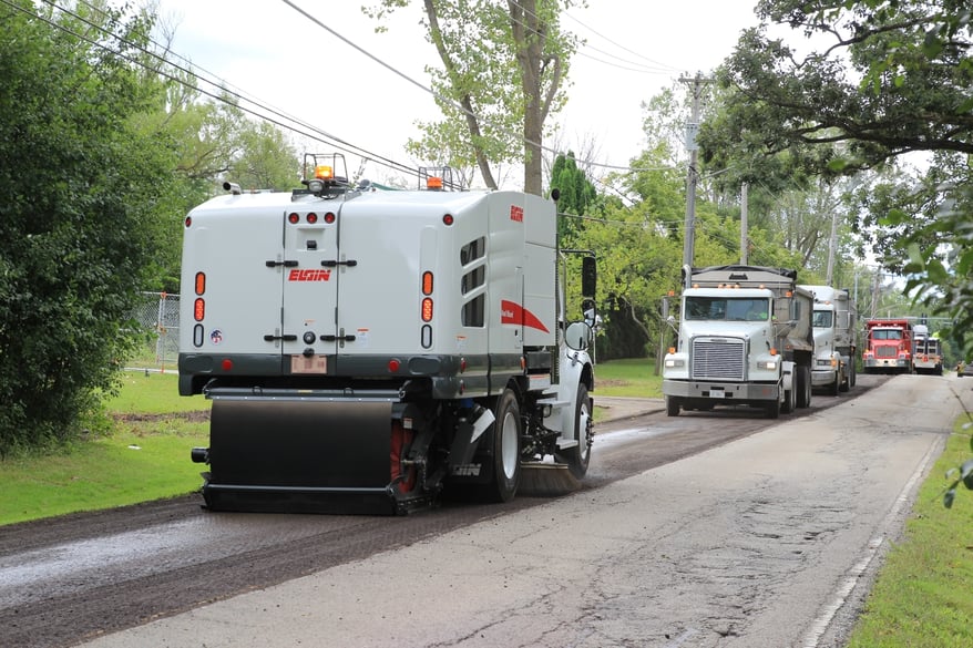 A 4 wheel mechanical Elgin Sweeper cleaning up millings